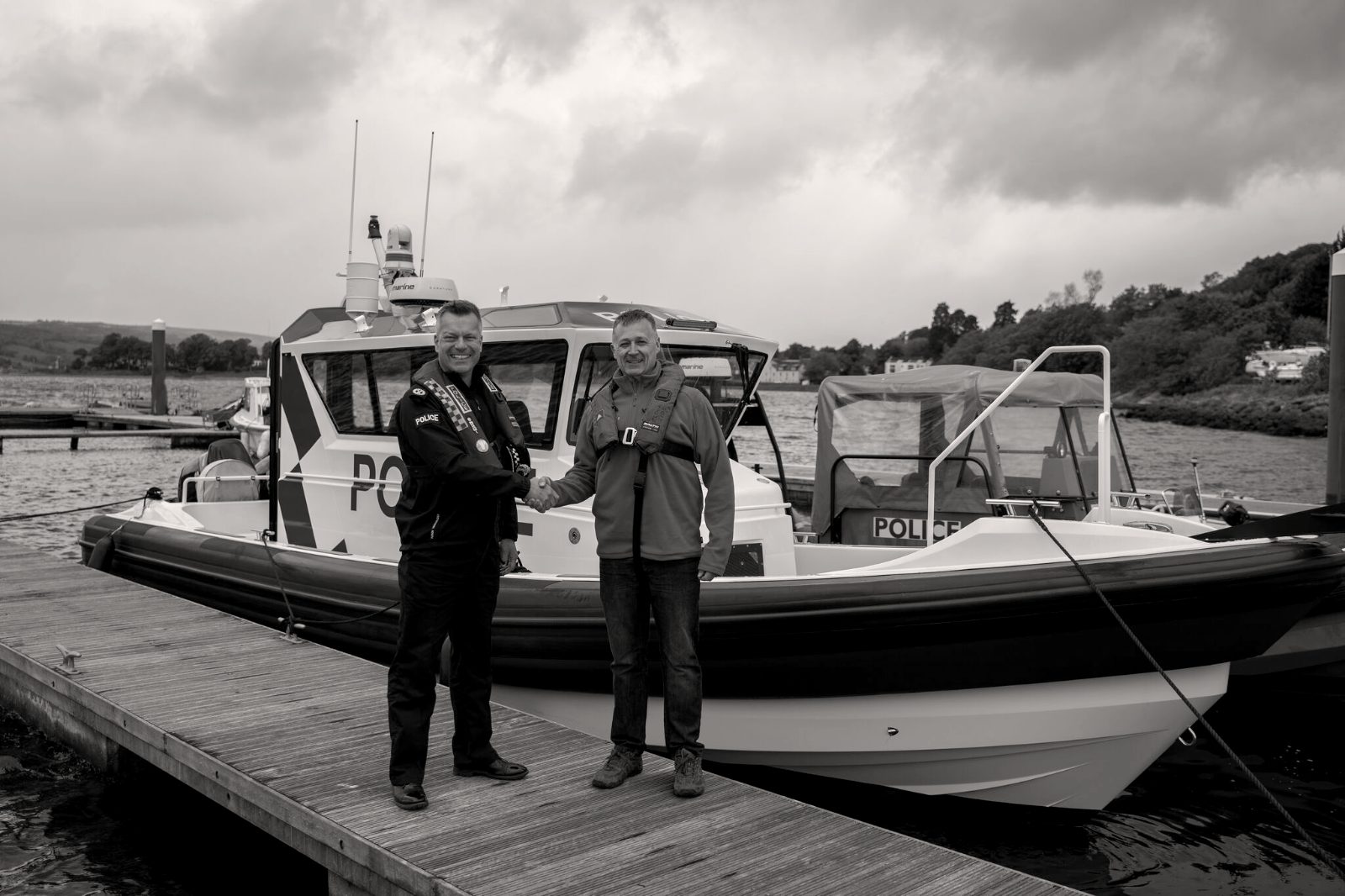 Jason Purvey shaking hands with a senior police officer at the handover of a new police patrol boat